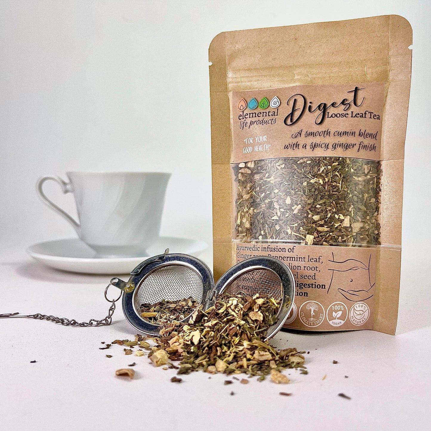 Elemental Life Product's Digest loose leaf tea blend with Ginger, Peppermint, and Cumin seed with a tea ball and tea cup