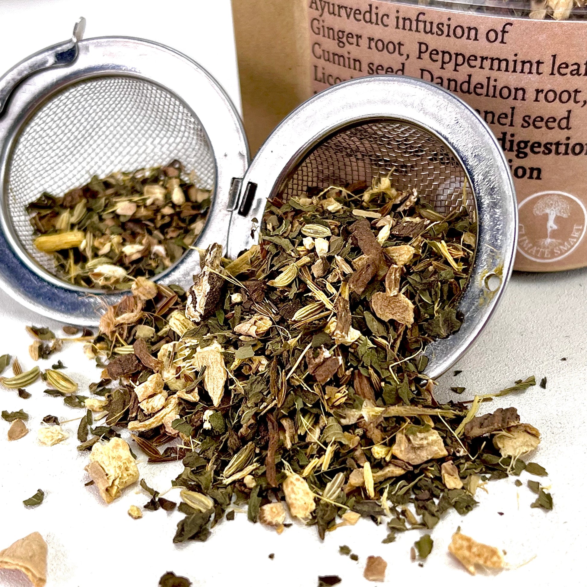 Digest loose leaf tea with Ginger, Peppermint, Cumin, Dandelion, Licorice, & Fennel in an open tea ball strainer.