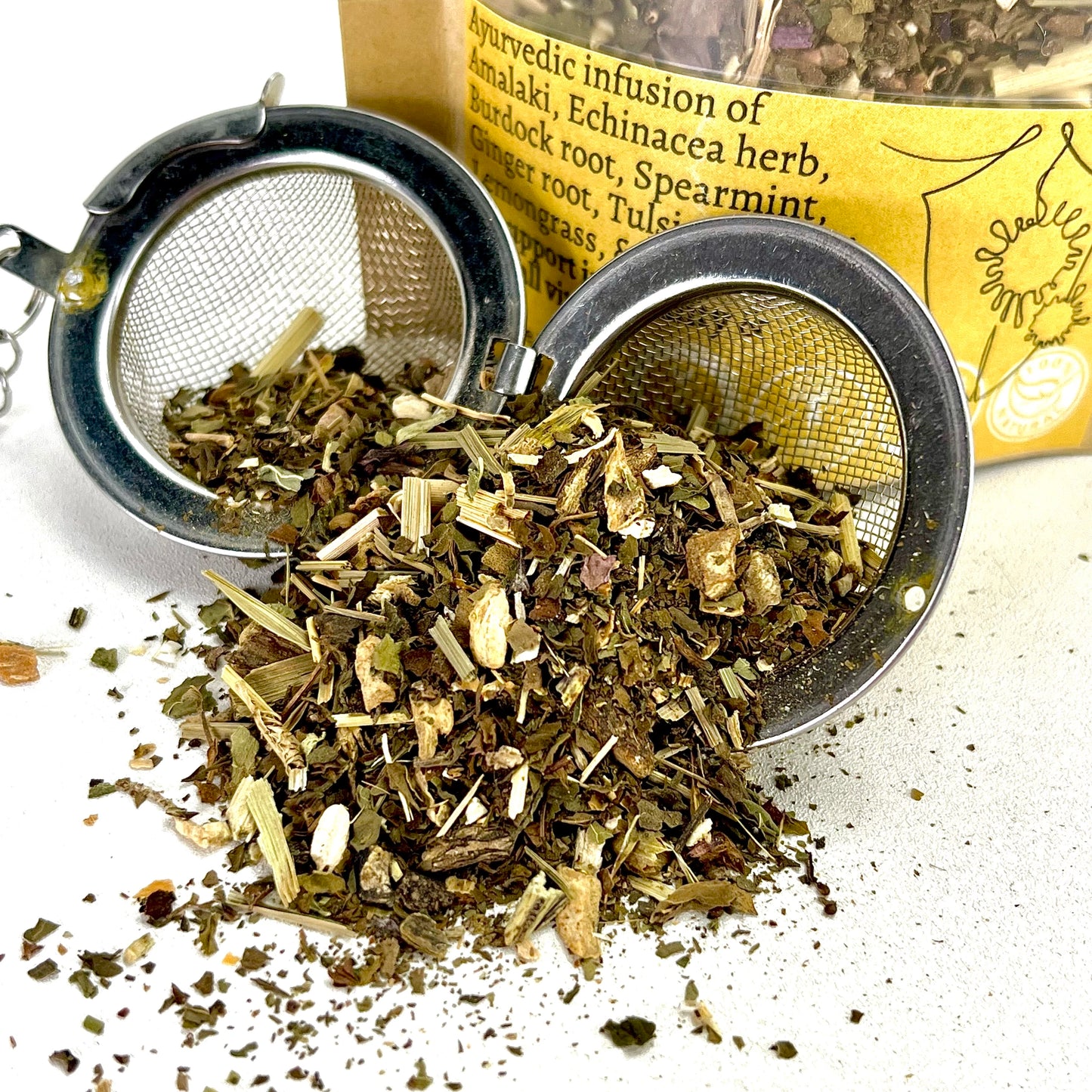 A loose leaf tea blend of Burdock root, Spearmint, Ginger root, Tulsi, Guduchi, Lemongrass, & Ashwagandha in an open tea ball